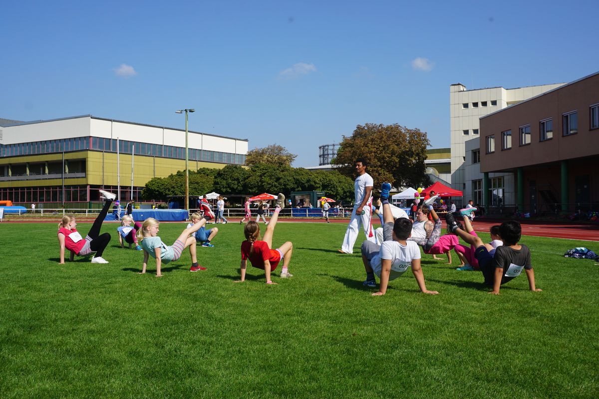 ein Capoeira Maestro zeigt Kindern die Sportart