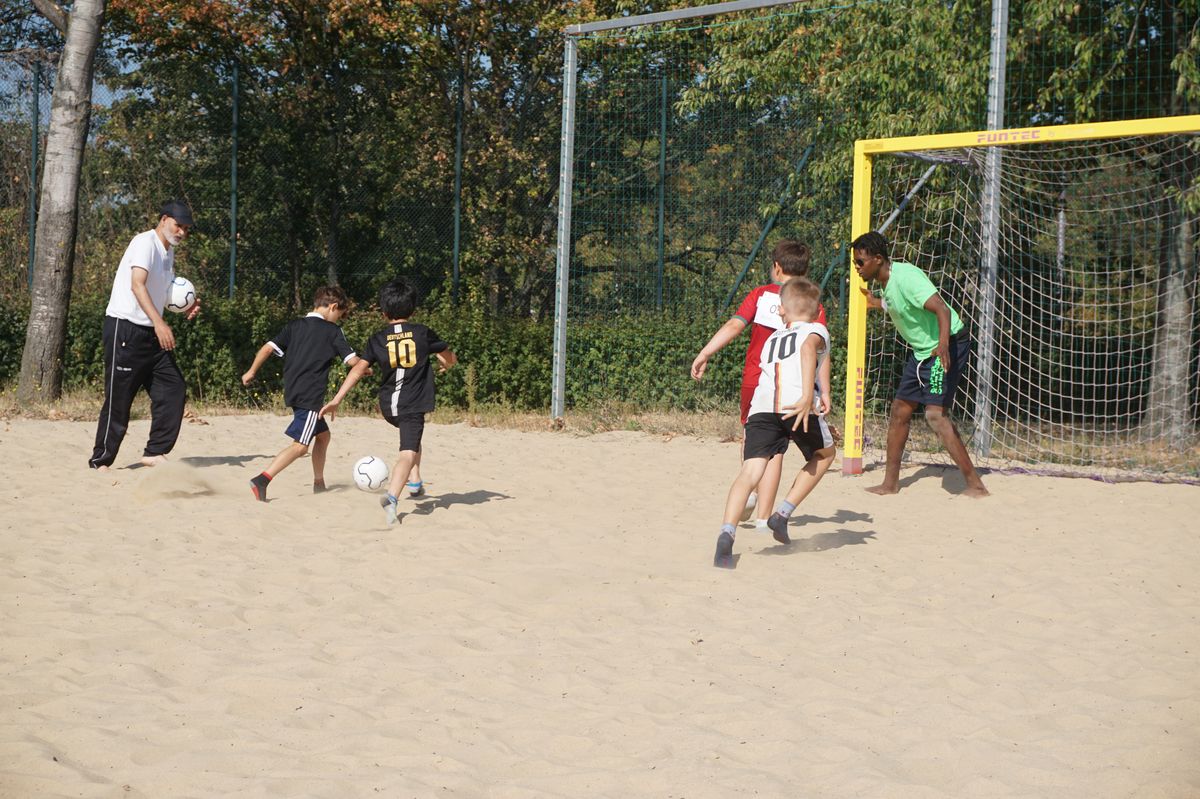 Kinder spielen Fußball im Sand